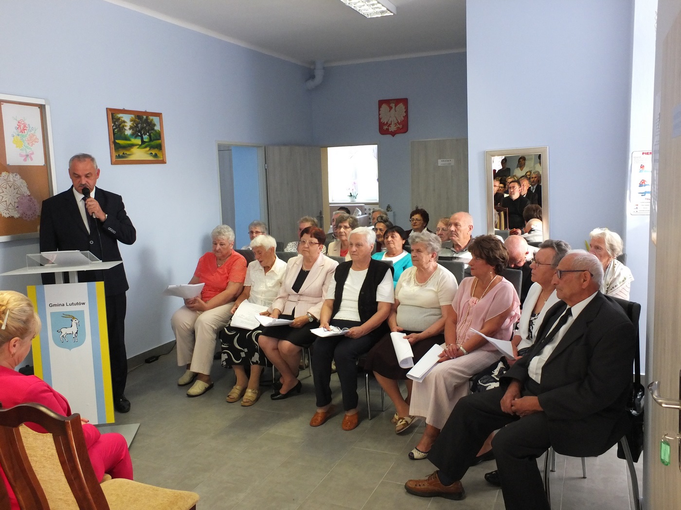 grupa osób, uczestników Dziennego Domu Pomocy w budynku Domu podczas przemówienia wójta Gminy Lututów