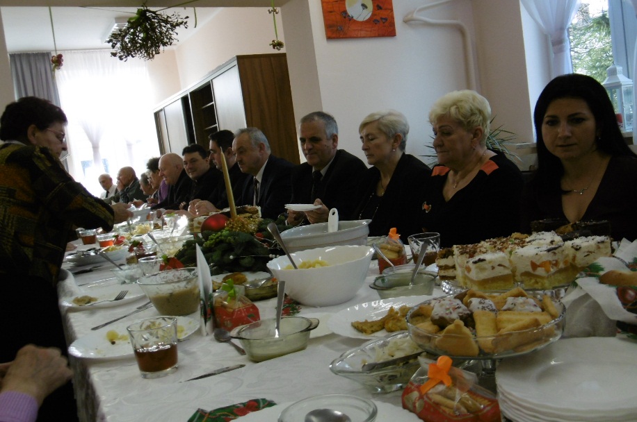 grupa osób,w tym uczestników DDP przy stole podczas kolacji wigilijnej